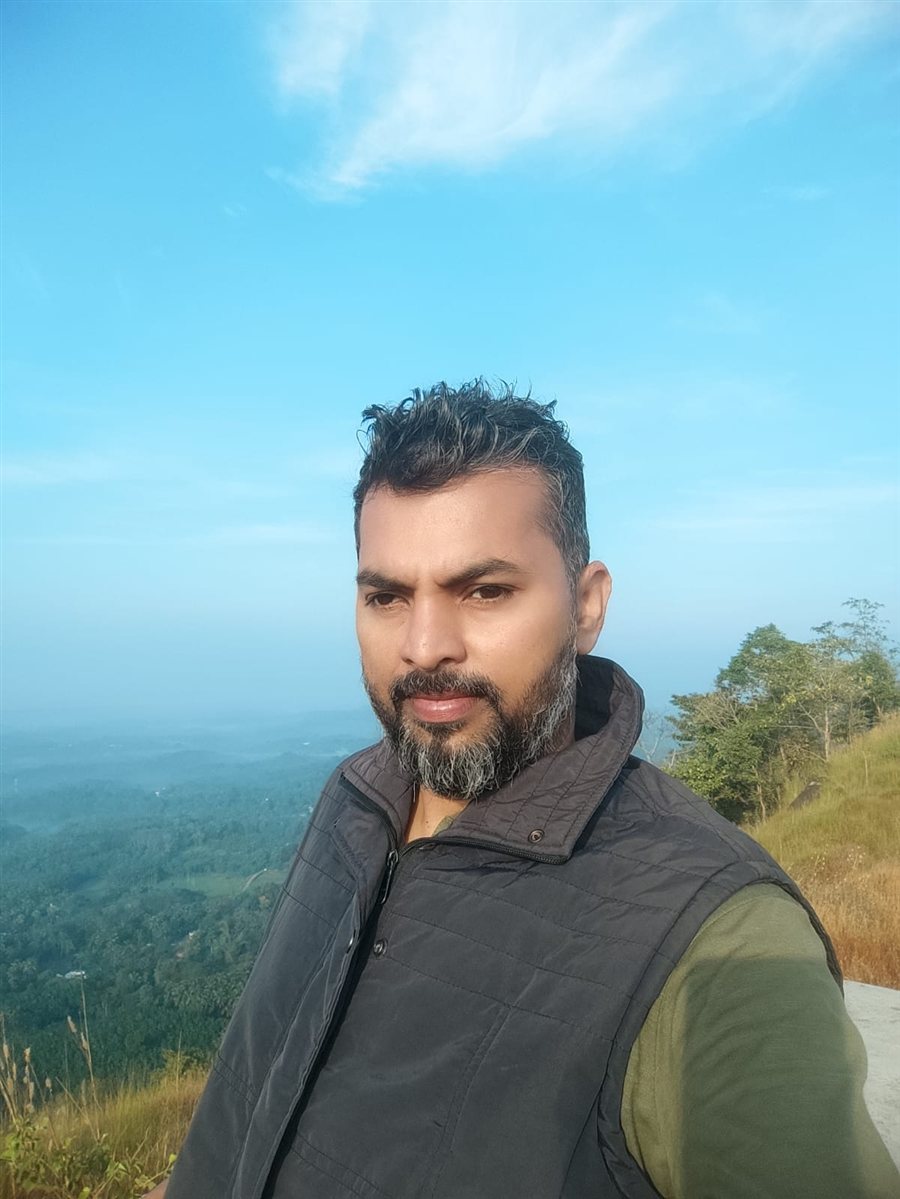 Abhilash CR on a hilltop overlooking green valleys