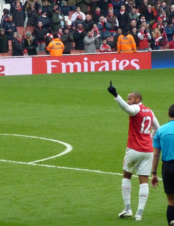 Thierry Henry in Arsenal's red and white, raising a finger to the crowd